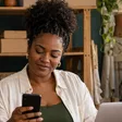 Empreendedora com celular entre caixas de sua loja virtual