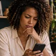 Profissional com celular e notebook em seu ambiente de trabalho